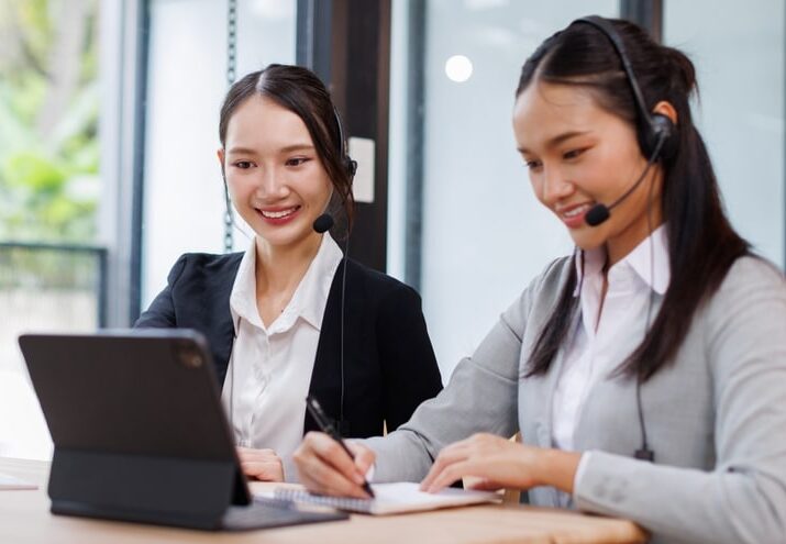 Asian woman virtual legal assistant wearing a headset, working at a desk in a professional office.