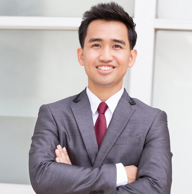 A professional male virtual legal assistant in a light blue suit blazer leaning against an office wall, representing confident and reliable legal administrative support.