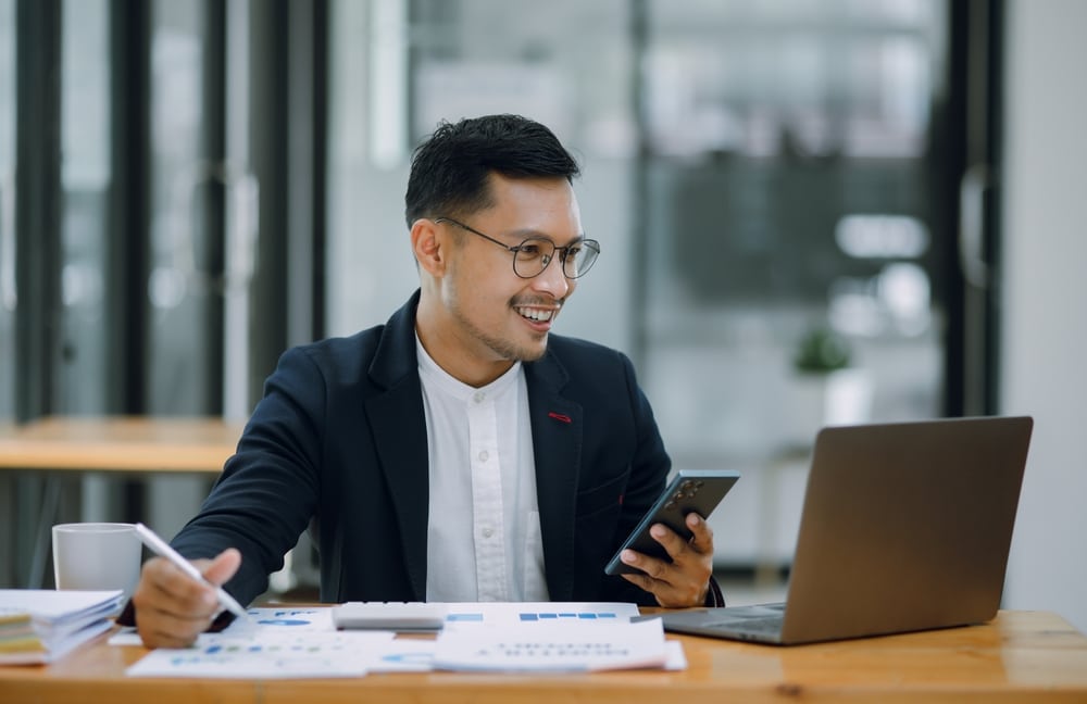a male in a corporate suit using a laptop and smartphone to manage legal documentation and case tracking.