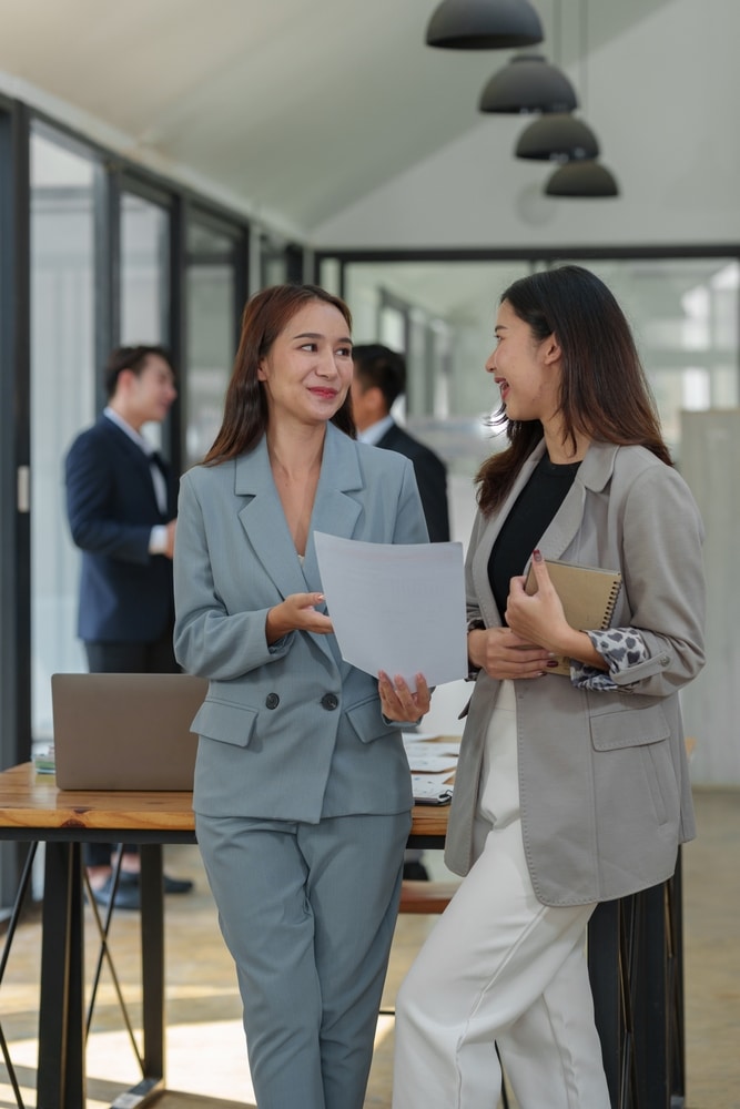 Two virtual legal assistants discussing work and analyzing documents in a professional setting.